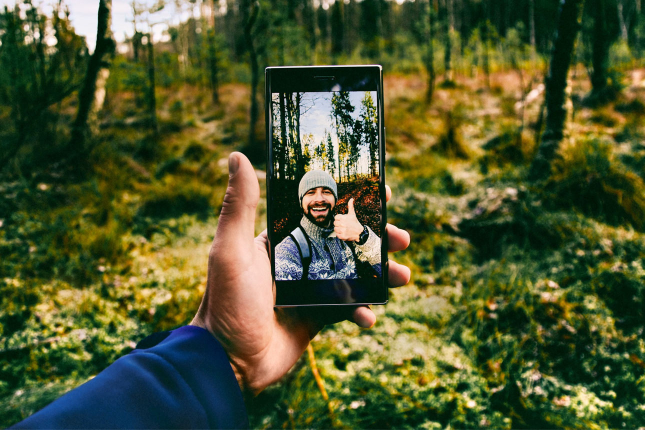 Ein Mann macht ein Selfie mit seinem Smartphone im Wald.
