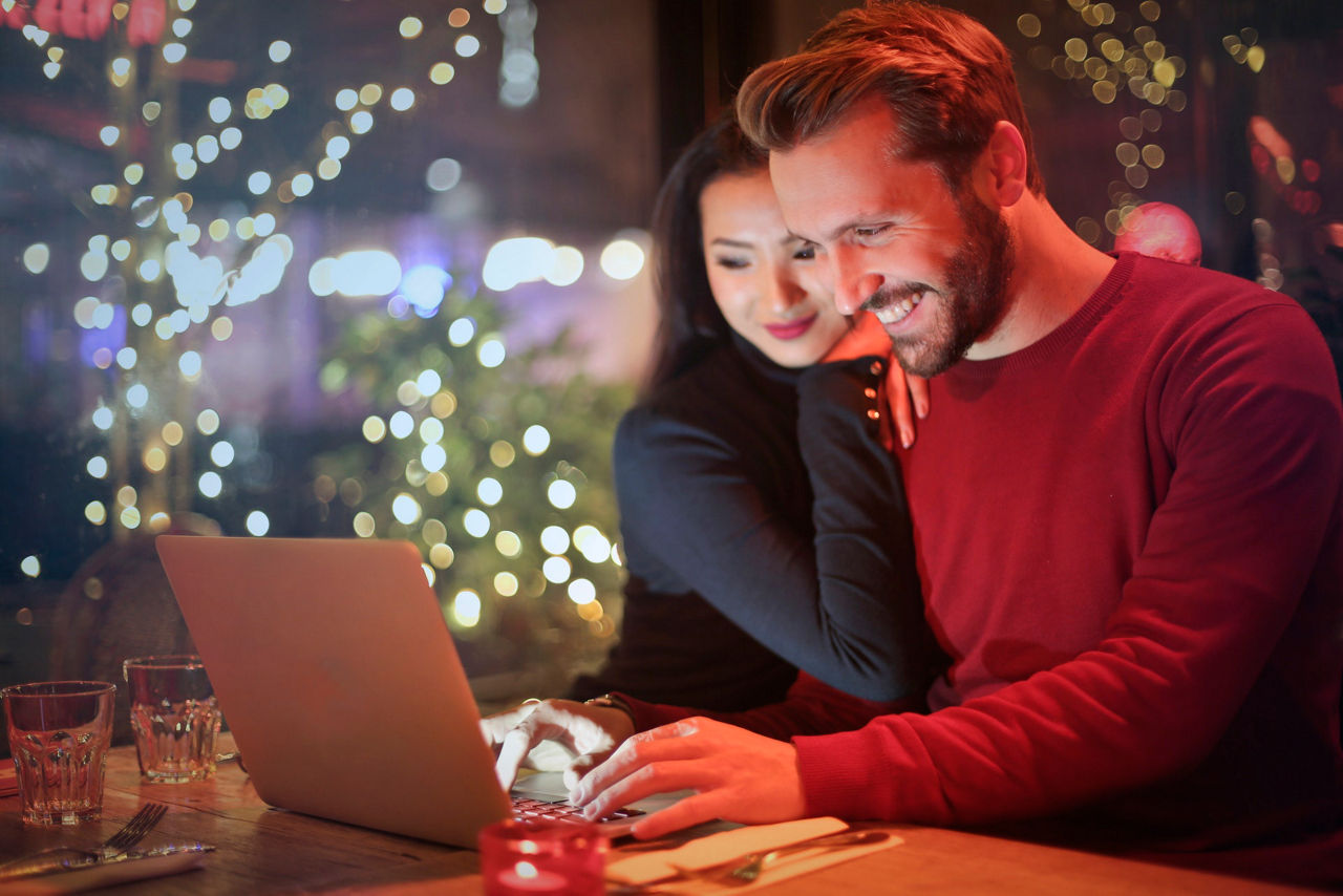 Ein Mann und eine Frau sitzen vor einem Laptop.