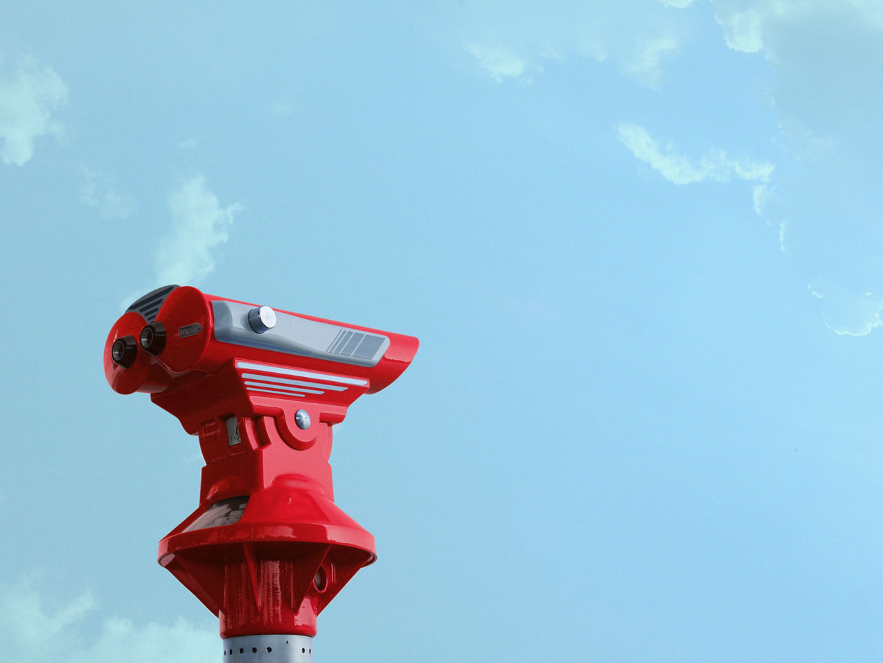 Ein rotes verankertes Fernglas ist zu sehen, im Hintergrund der blaue Himmel.
