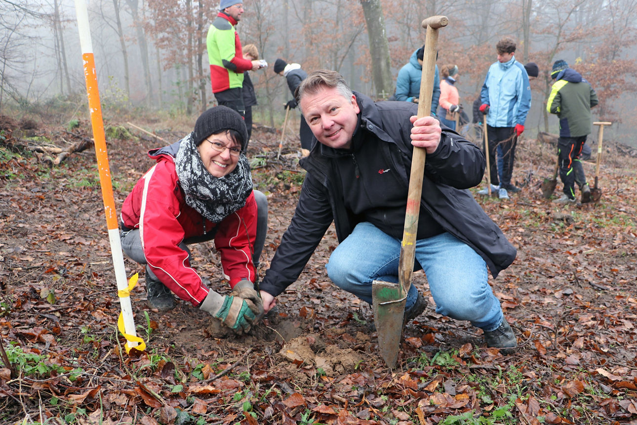 Petra Reutter (Nachhaltigkeitsbeauftragte unserer Bank) und Alexander Pahl (Teamleiter Marketing) setzen Baumsetzling im Wald