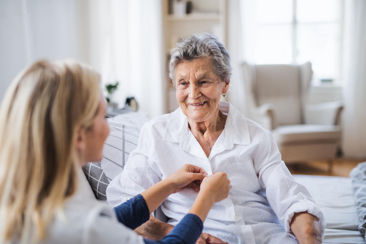 Pflegekraft hilft einer Seniorin beim Anziehen