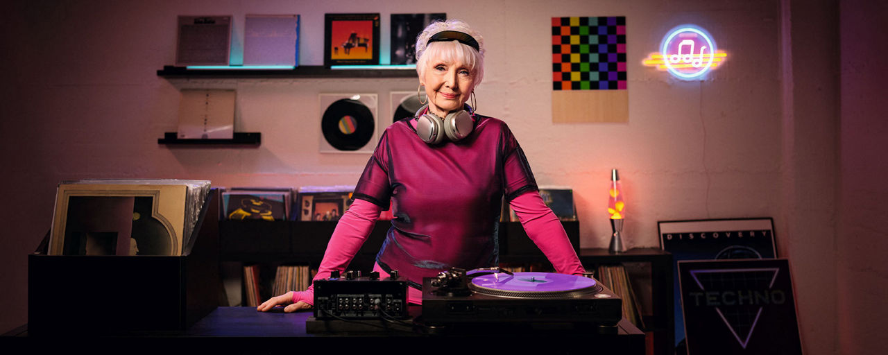 Eine ältere Frau mit Kopfhörern an einem DJ-Pult