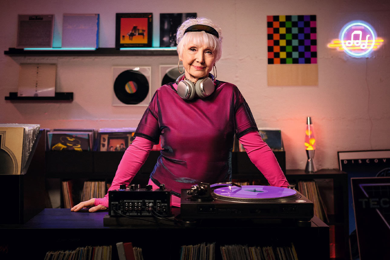 Eine ältere Frau mit Kopfhörern an einem DJ-Pult Eine ältere Frau mit Kopfhörern an einem DJ-Pult