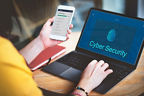 Frau sitzt an einem Laptop auf dem "Cyber security" zu lesen ist