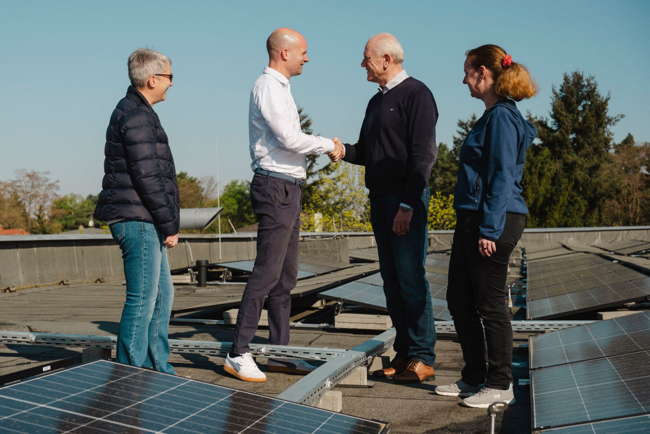 Händeschüttelnde Menschen vor Photovoltaikanlagen