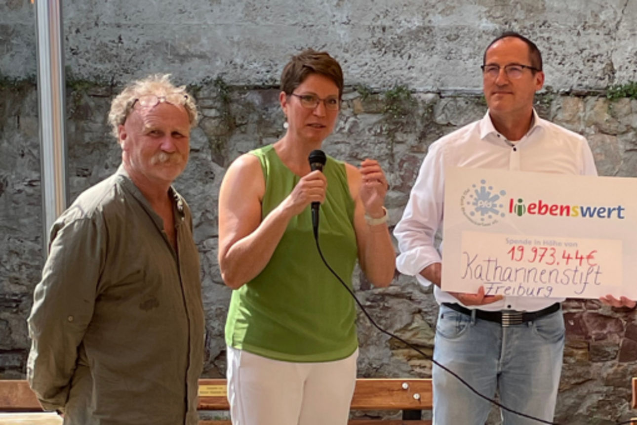 Eine Gruppe von Menschen steht zusammen und hält Spendenschecks in den Händen.