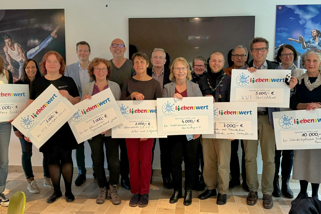 Eine Gruppe von Menschen steht zusammen und hält Spendenschecks in den Händen.