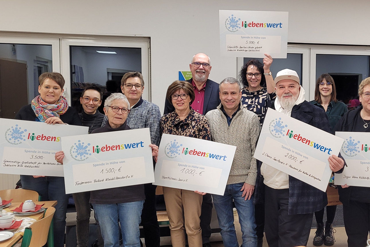 Eine Gruppe von Menschen steht zusammen und hält Spendenschecks in den Händen.