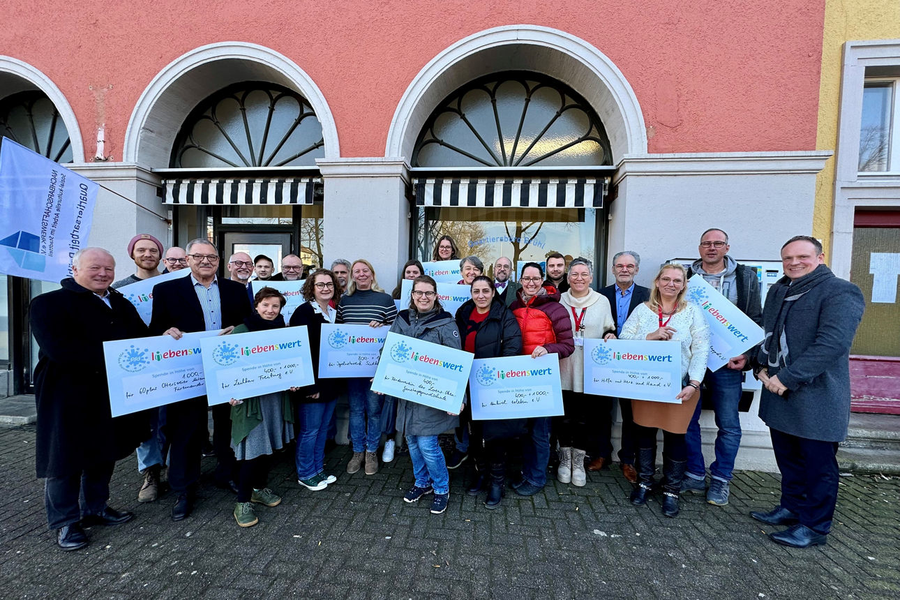 Eine Gruppe von Menschen steht zusammen und hält Spendenschecks in den Händen.