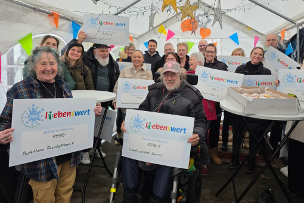 Mehrere Menschen halten symbolische Schecks in den Händen 