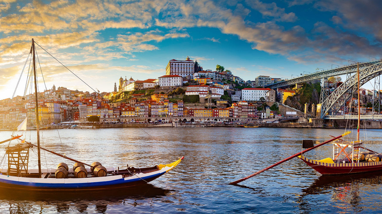 Skyline von Porto über den Fluss betrachtet mit zwei typisch portugisischen Booten im Vordergrund