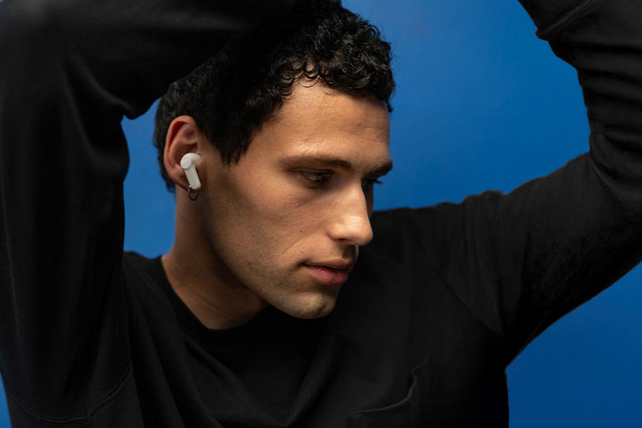 Ein junger Mann hat In-Ear-Kopfhörer im Ohr