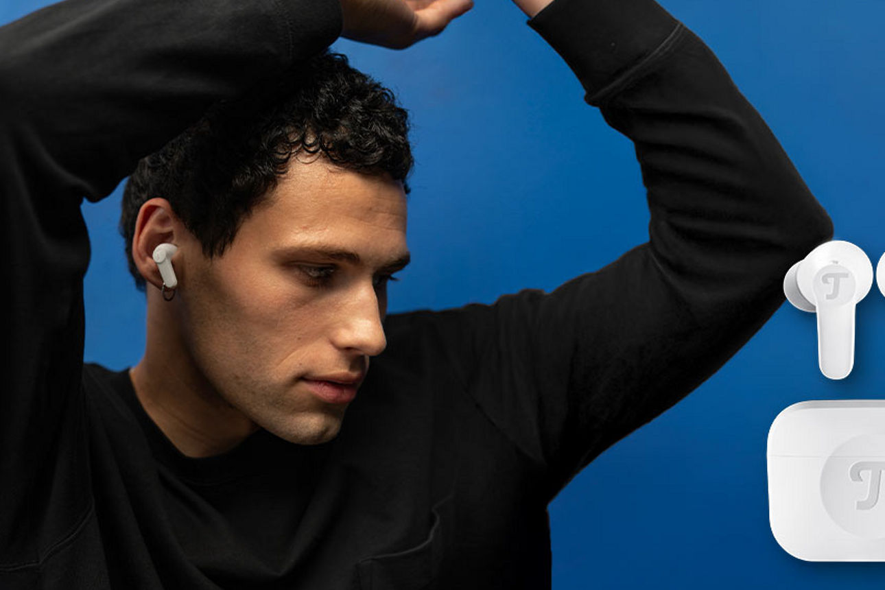 Person mit In-Ear-Kopfhörern bewegt sich zur Musik vor blauem Wand