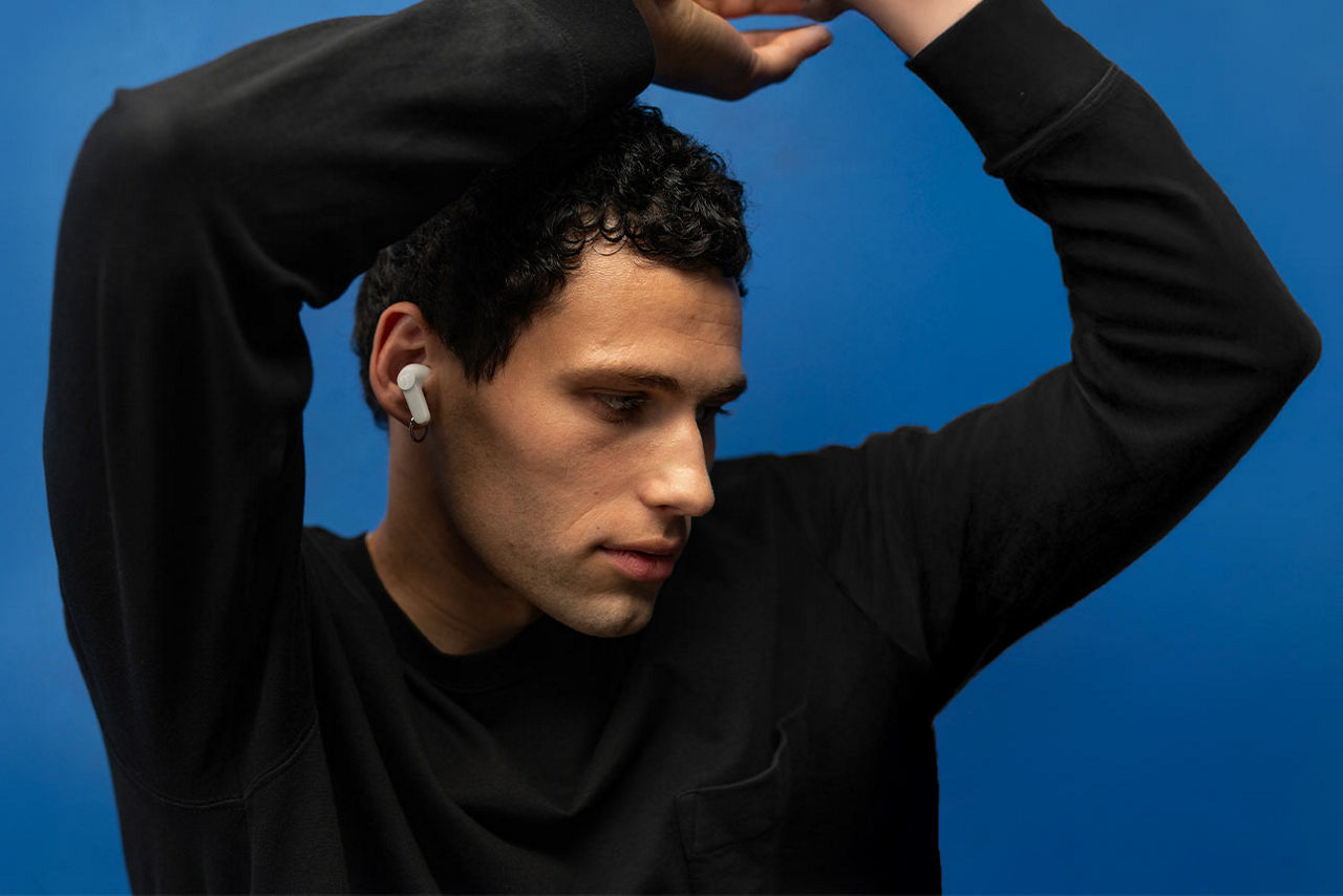 Junger Mann mit erhobenen Armen und Darstellung von in-ears-Kopfhörer