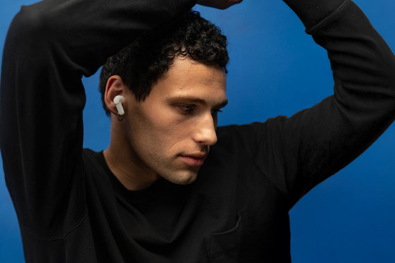 Junger Mann im schwarzen Pullover mit Teufel In-Ear-Kopfhörern