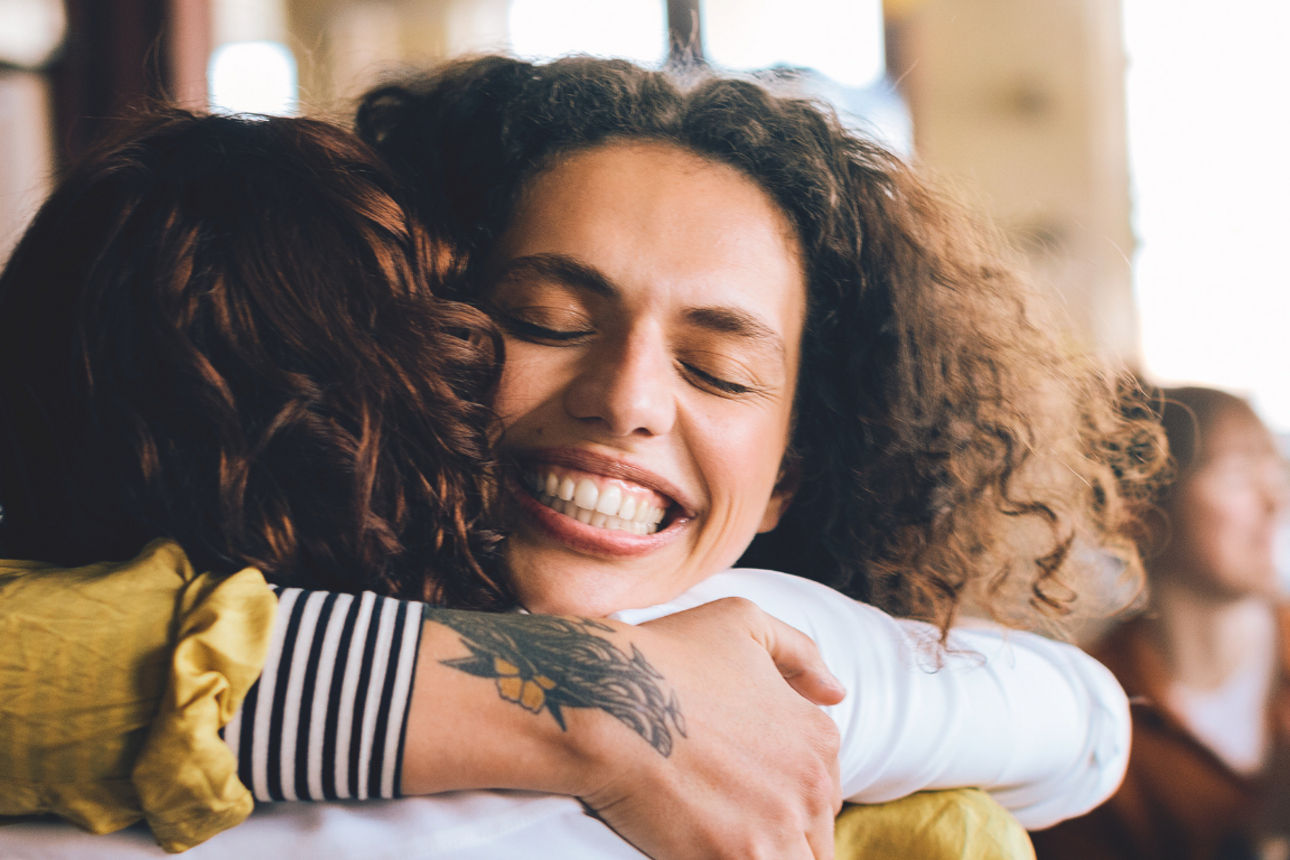 Zwei Personen umarmen sich erfreut.