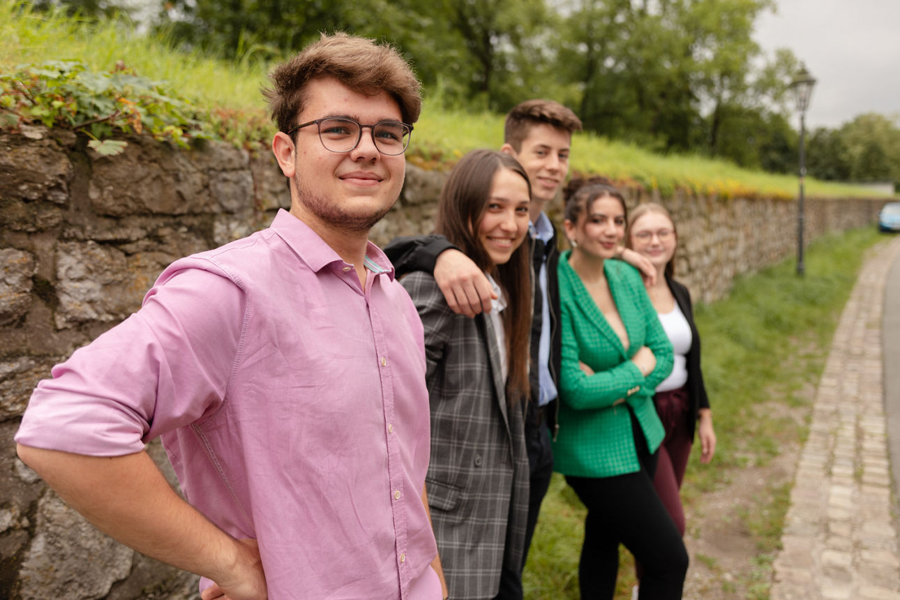 Azubis in bunten Kleidern stehen draußen in einer Reihe