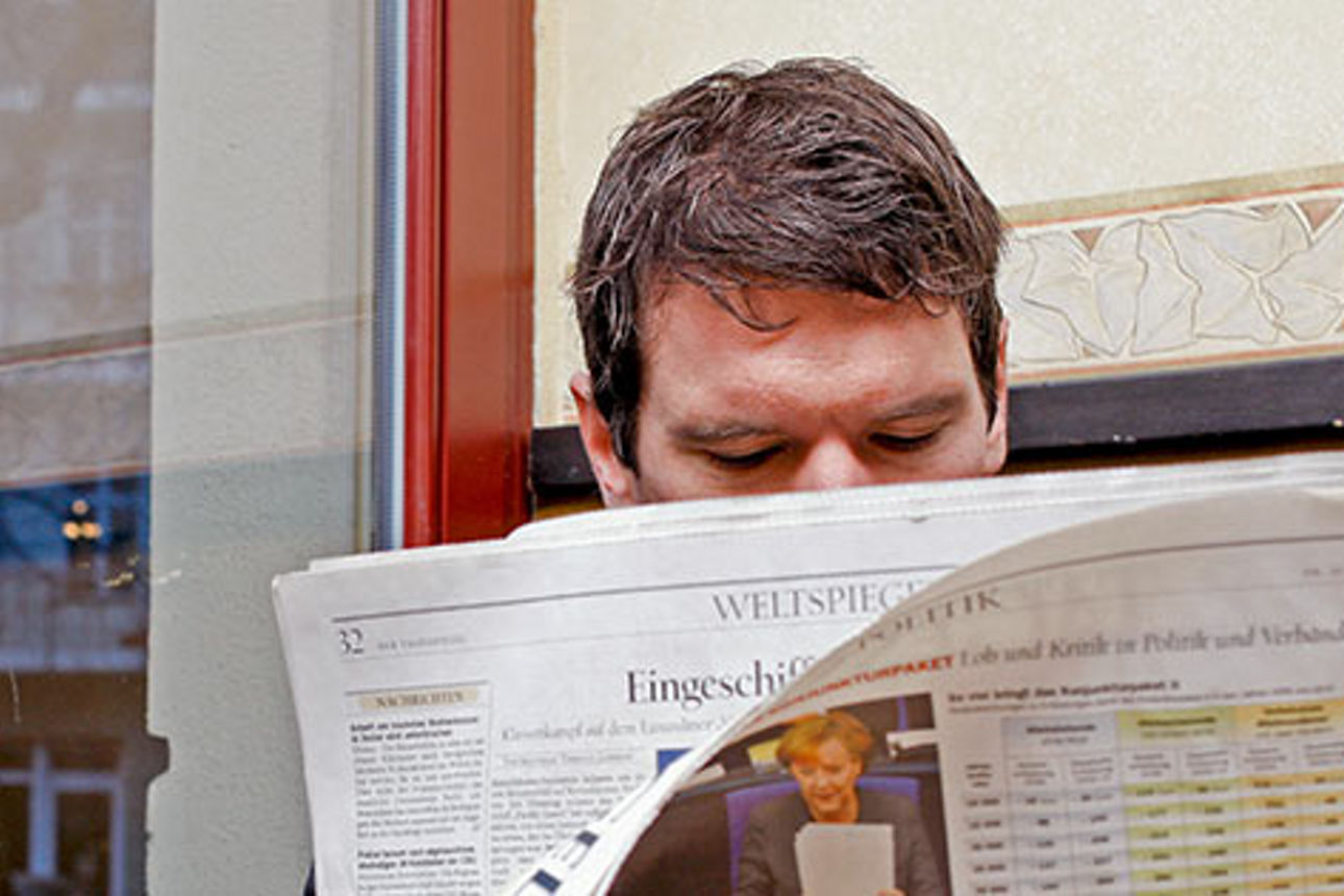Ein Mann sitzt und liest eine Zeitung