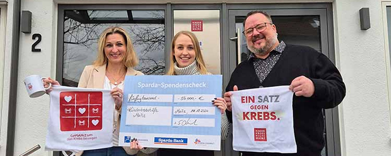 2 Frauen und 1 Mann halten Plakate der Kinderkrebshilfe Mainz und einen Scheck
