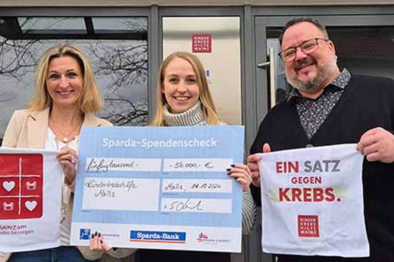 2 Frauen und 1 Mann halten Plakate der Kinderkrebshilfe Mainz und einen Scheck