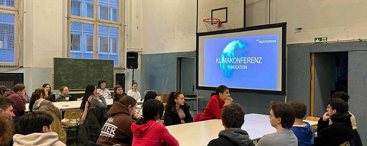Halle voller Schüler mit Schrift Klimapolitik auf großem Screen