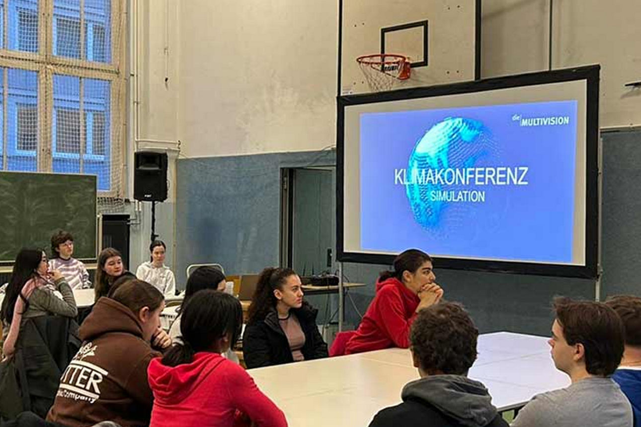 Halle voller Schüler mit Schrift Klimapolitik auf großem Screen
