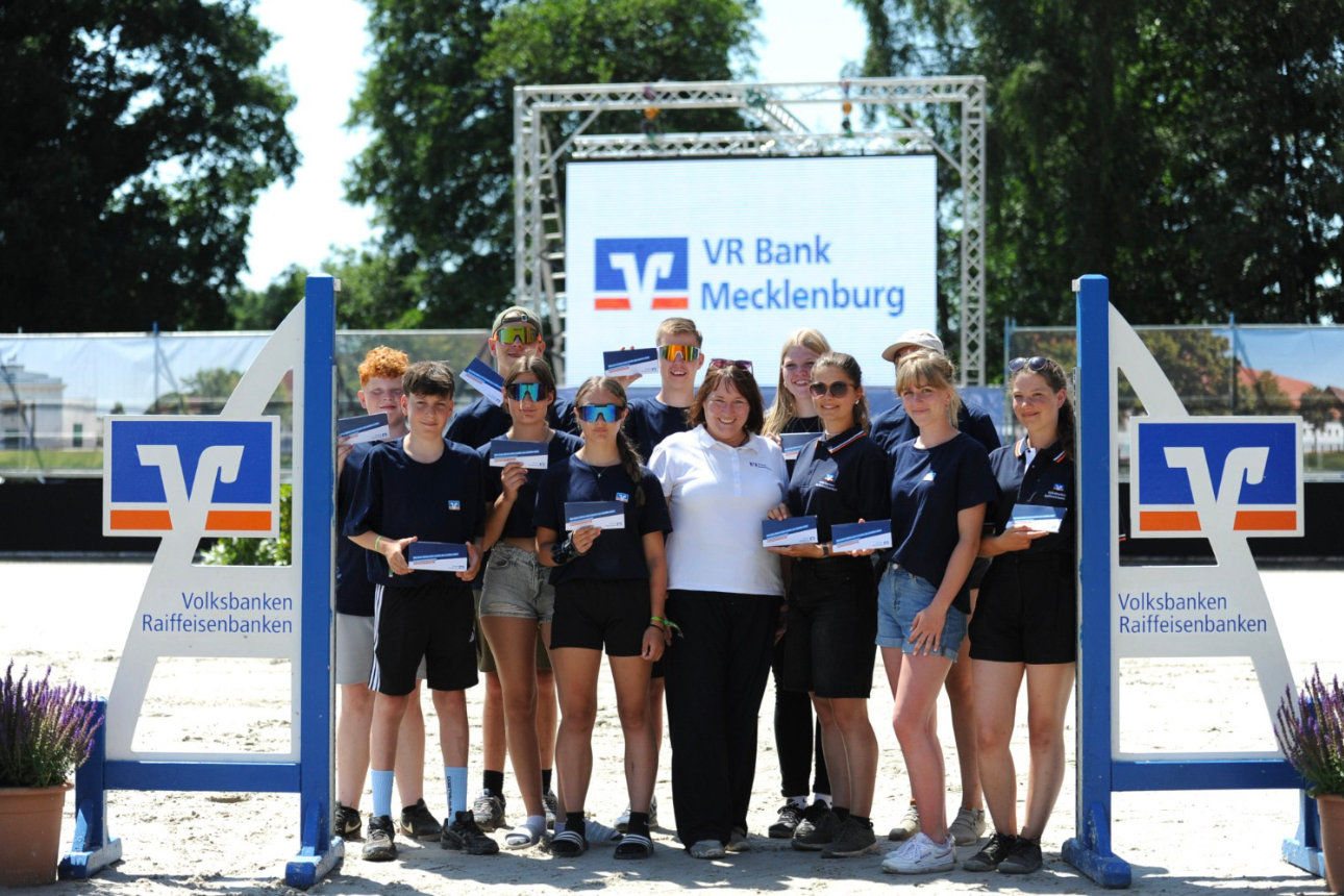 Elf Jugendliche stehen mit Bankmitarbeiterin auf dem Reitplatz in Redefin