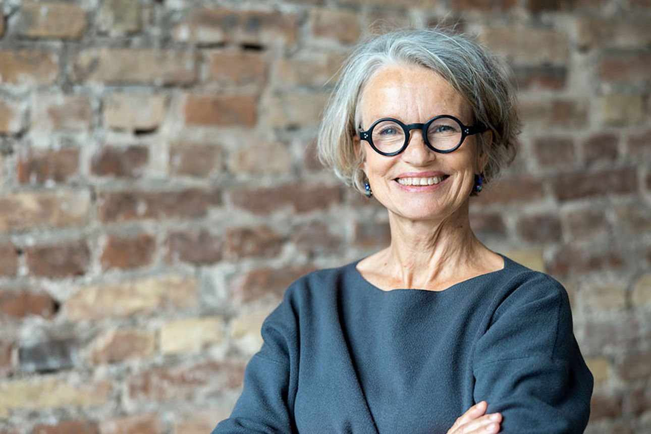 Eine lächelnde Frau vor Mauerwerk