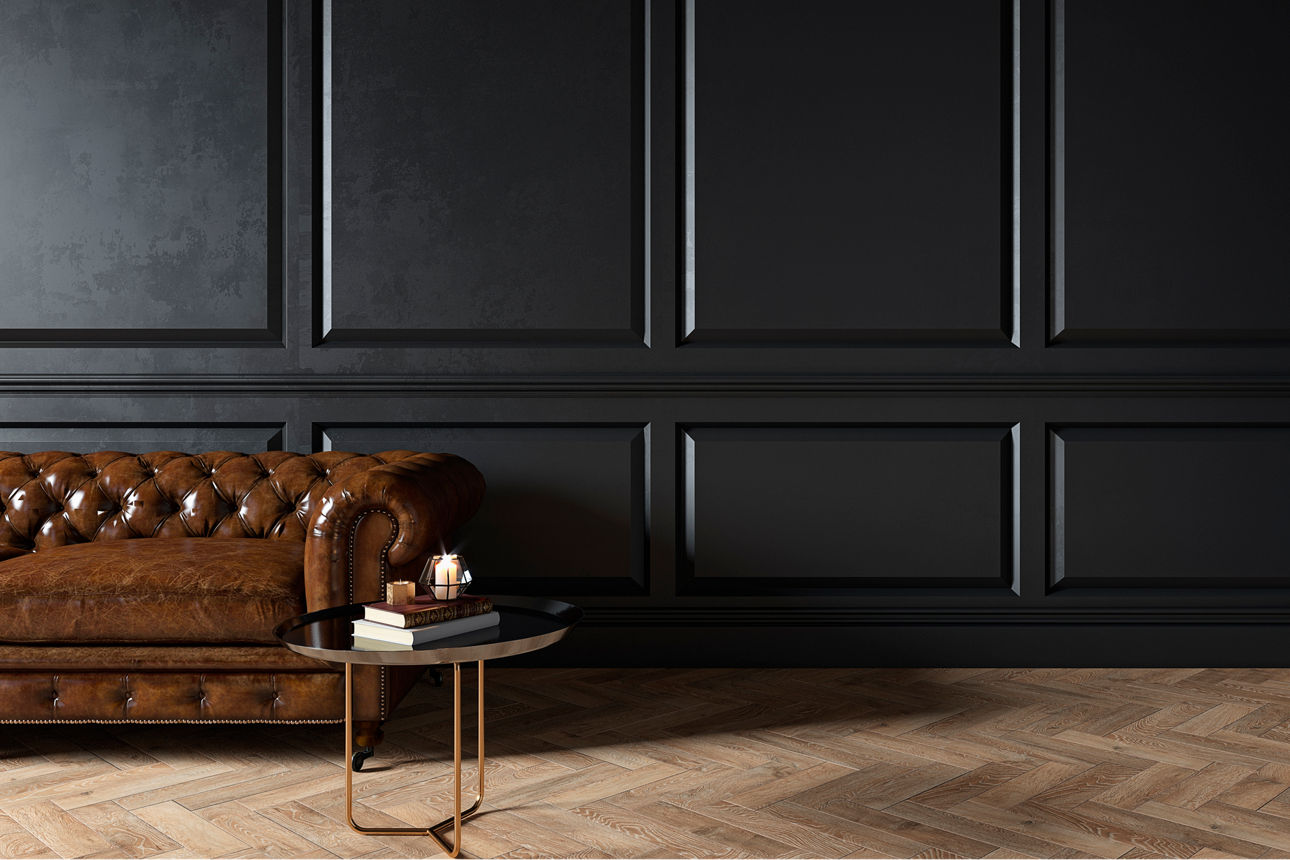 Eine braune Couch aus Leder und ein kleiner Tisch stehen vor einer Wand mit einer schwarzen Holztäfelung