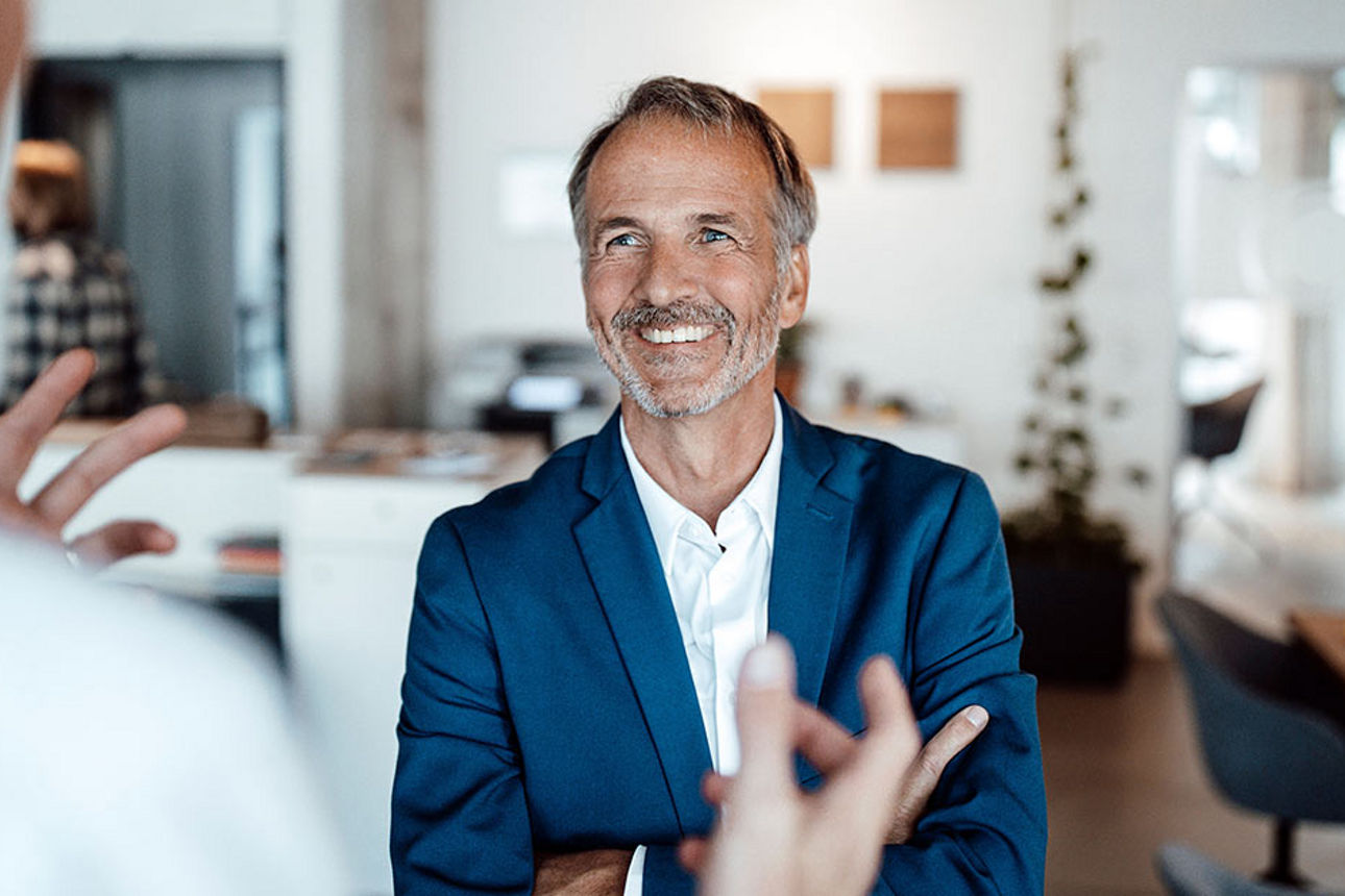 Älterer Mann sitzt lachend auf Landmaschine