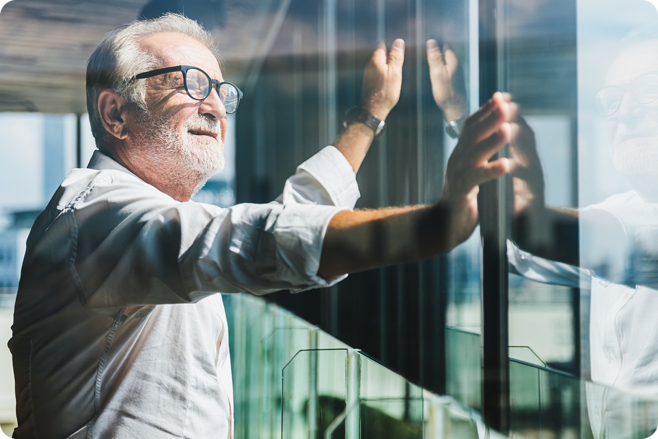 Ein Unternehmer steht in seinem Büro und schaut aus dem Fenster