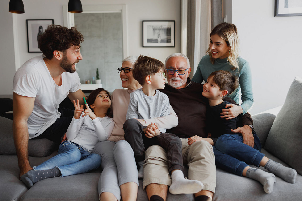 Eine Mehrgenerationenfamilie posiert auf dem Sofa in ihrem Wohnzimmer.