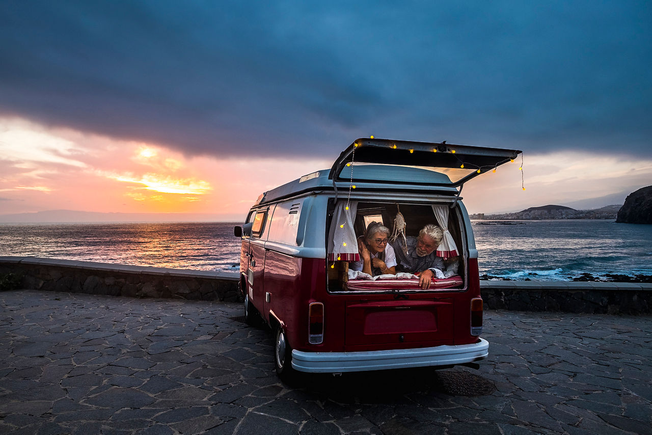 Älteres Paar schaut aus seinem Camper-Van mit Blick auf Strand und Meer