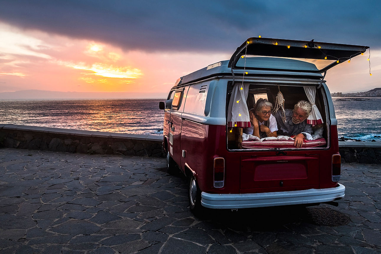 Älteres Paar schaut aus seinem Camper-Van mit Blick auf Strand und Meer