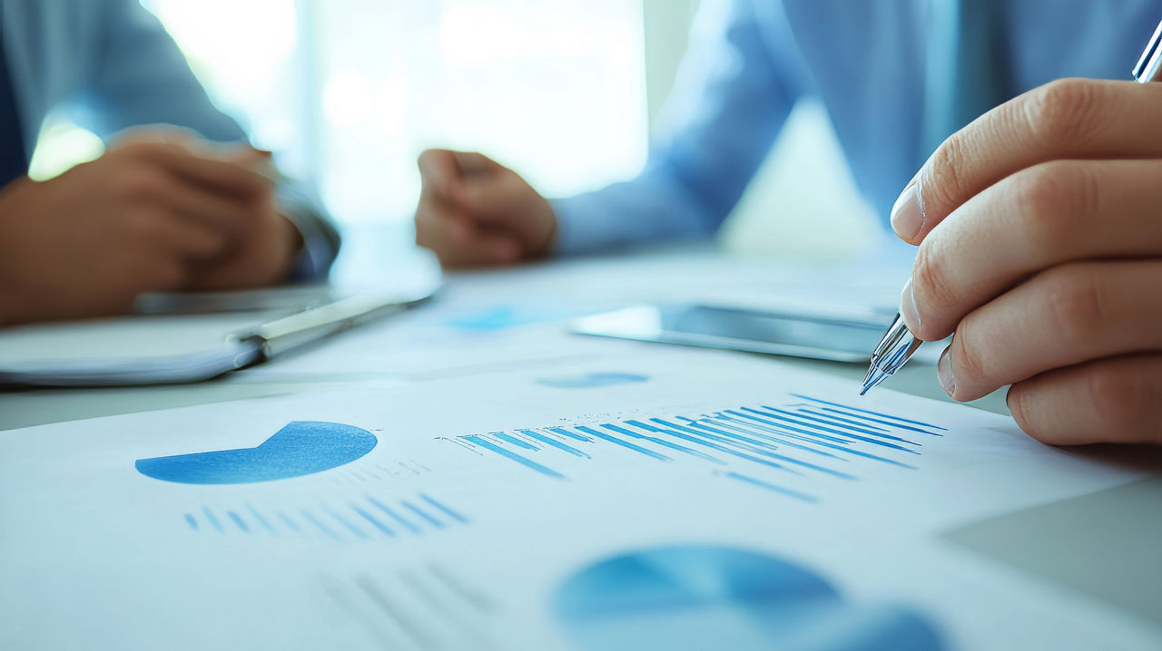 Hände liegen auf einem Dokument - in einer Hand ist ein Stift zum Zeigen auf die Unterlage gerichtet