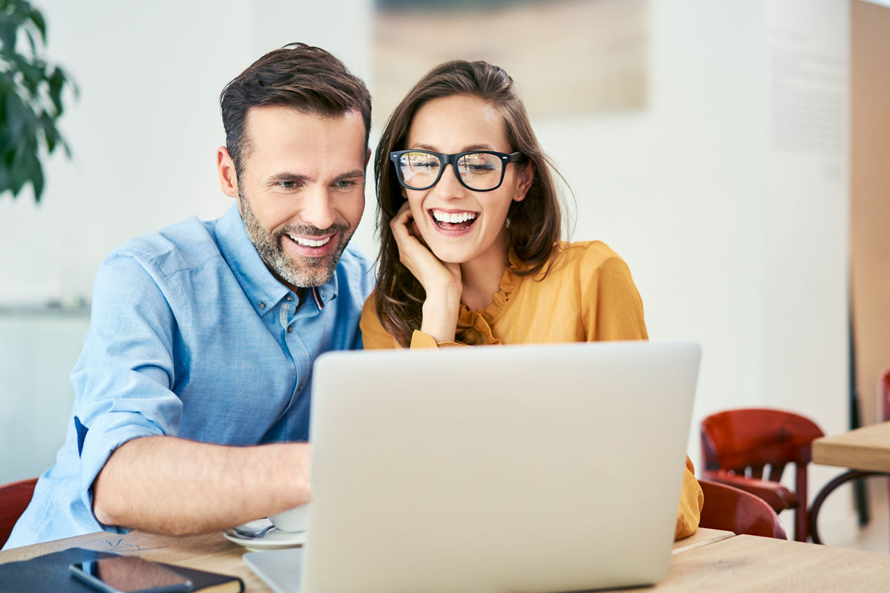 Lachendes Paar sitzt vor einem Laptop