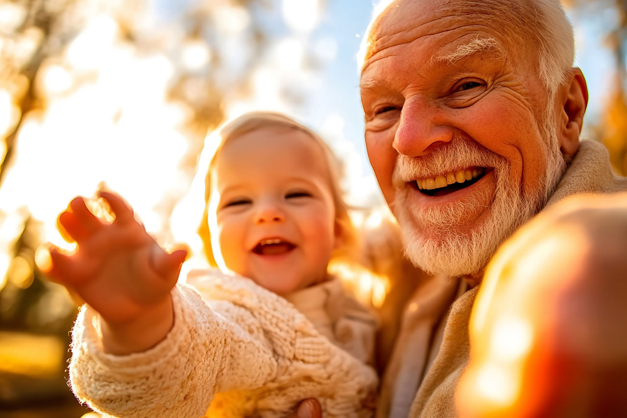 Älterer Herr hat ein Kleinkind auf dem Arm