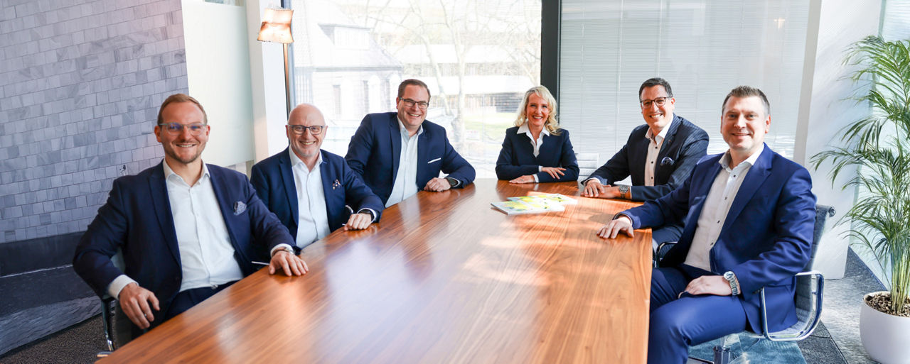 Die Führungsrunde des Private Wealth Managements sitzt an einem Besprechungstisch.