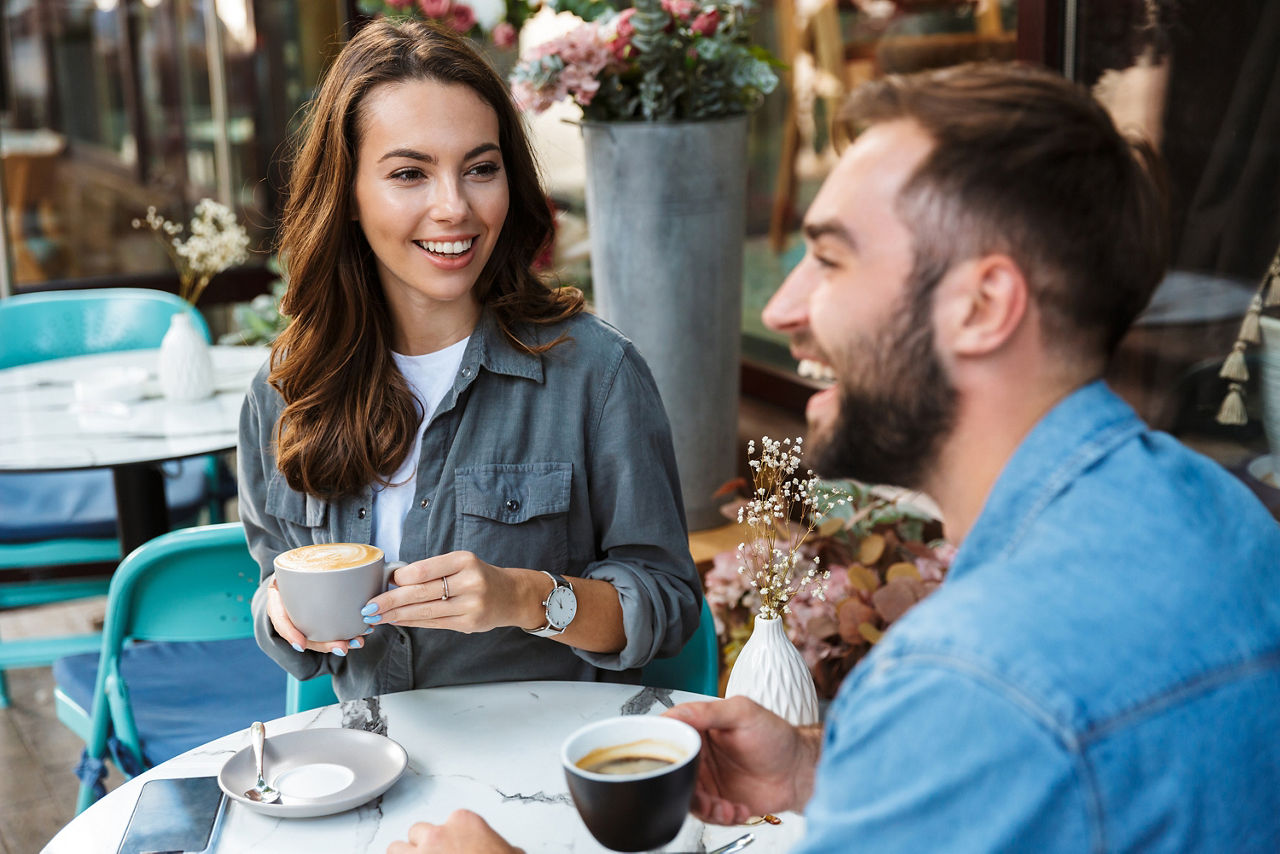 Eine Frau und ein Mann sitzen beim Kaffetrinken und lachen