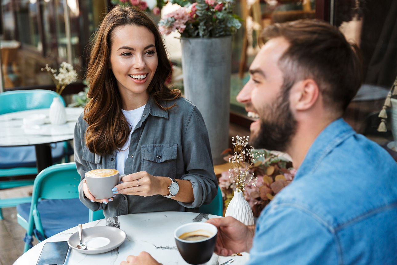 Eine Frau und ein Mann sitzen beim Kaffetrinken und lachen
