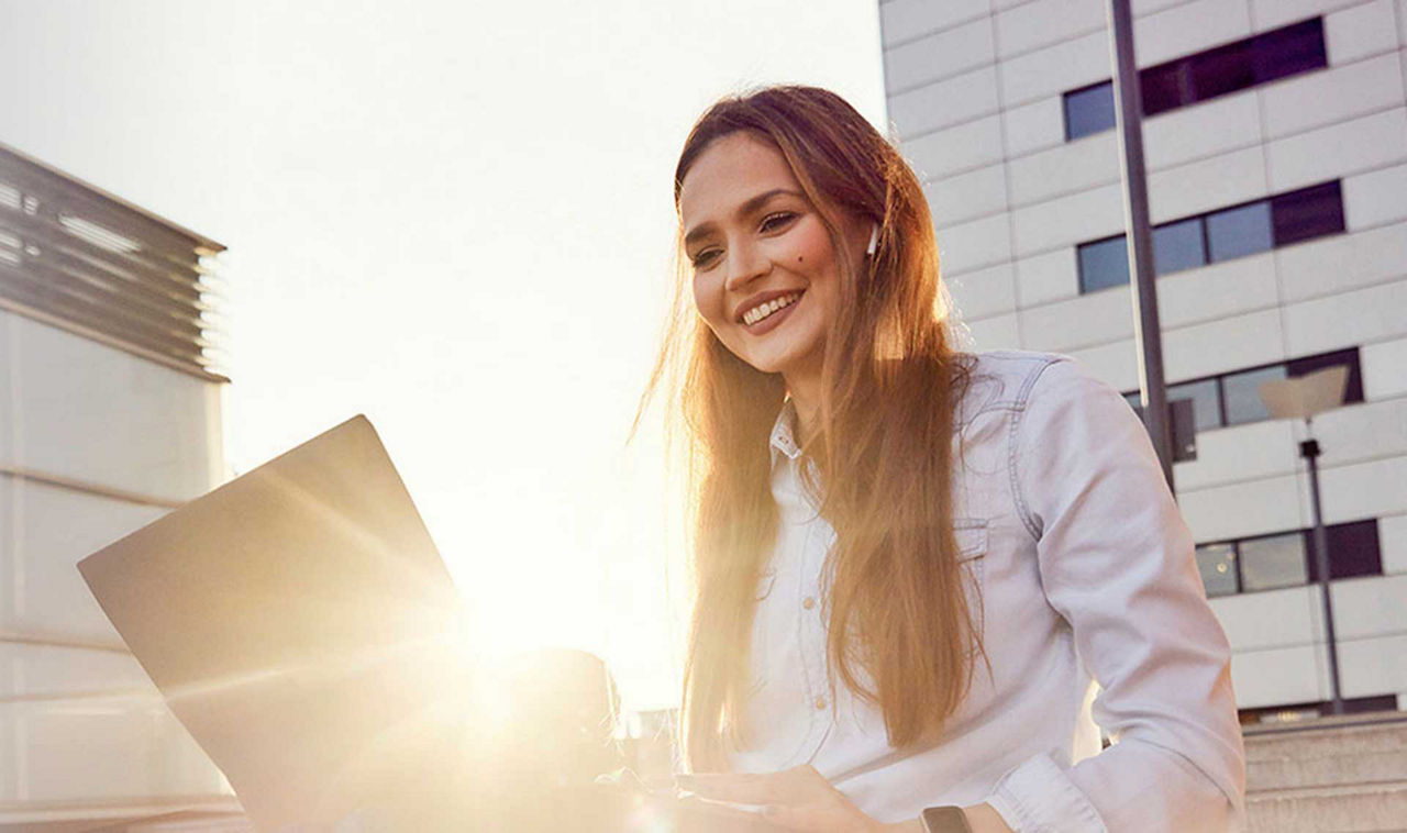 Digitalisierungskredit - Frau am Laptop draußen im Sonnenschein