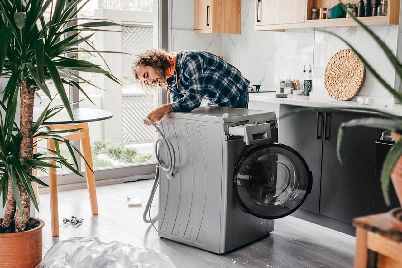 Ein Mann steht in der Küche und repariert eine Waschmaschine