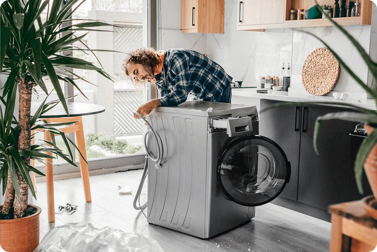 Ein Mann steht in der Küche und repariert eine Waschmaschine