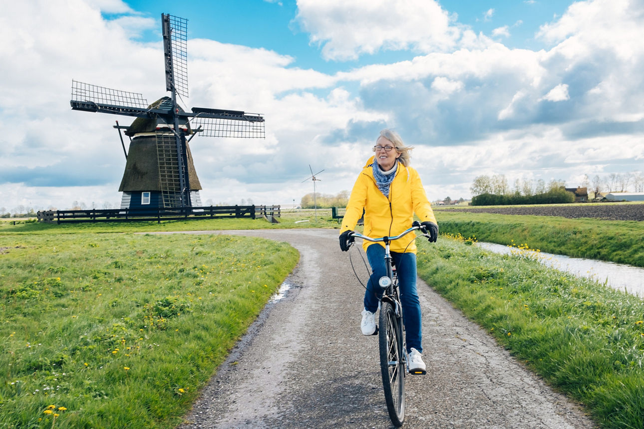 Frau auf einem Fahrrad vor einer Windmühle