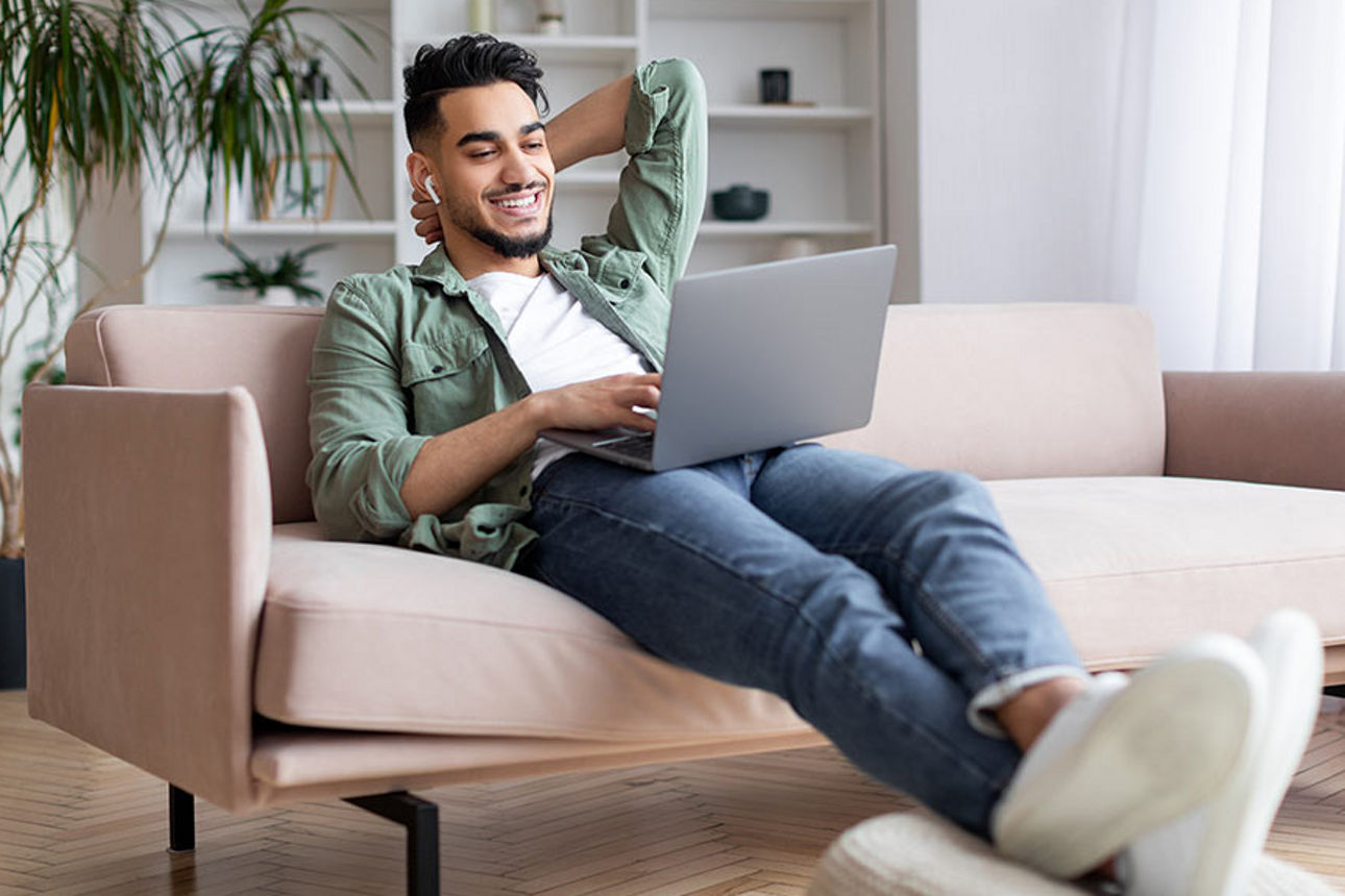 Mann mit Laptop auf einem Sofa