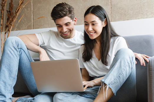 Mann und Frau mit Notebook vor dem Sofa