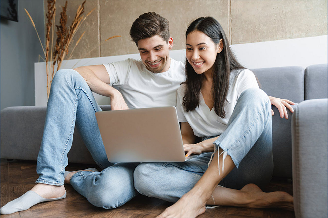 Mann und Frau mit Laptop auf dem Schoß
