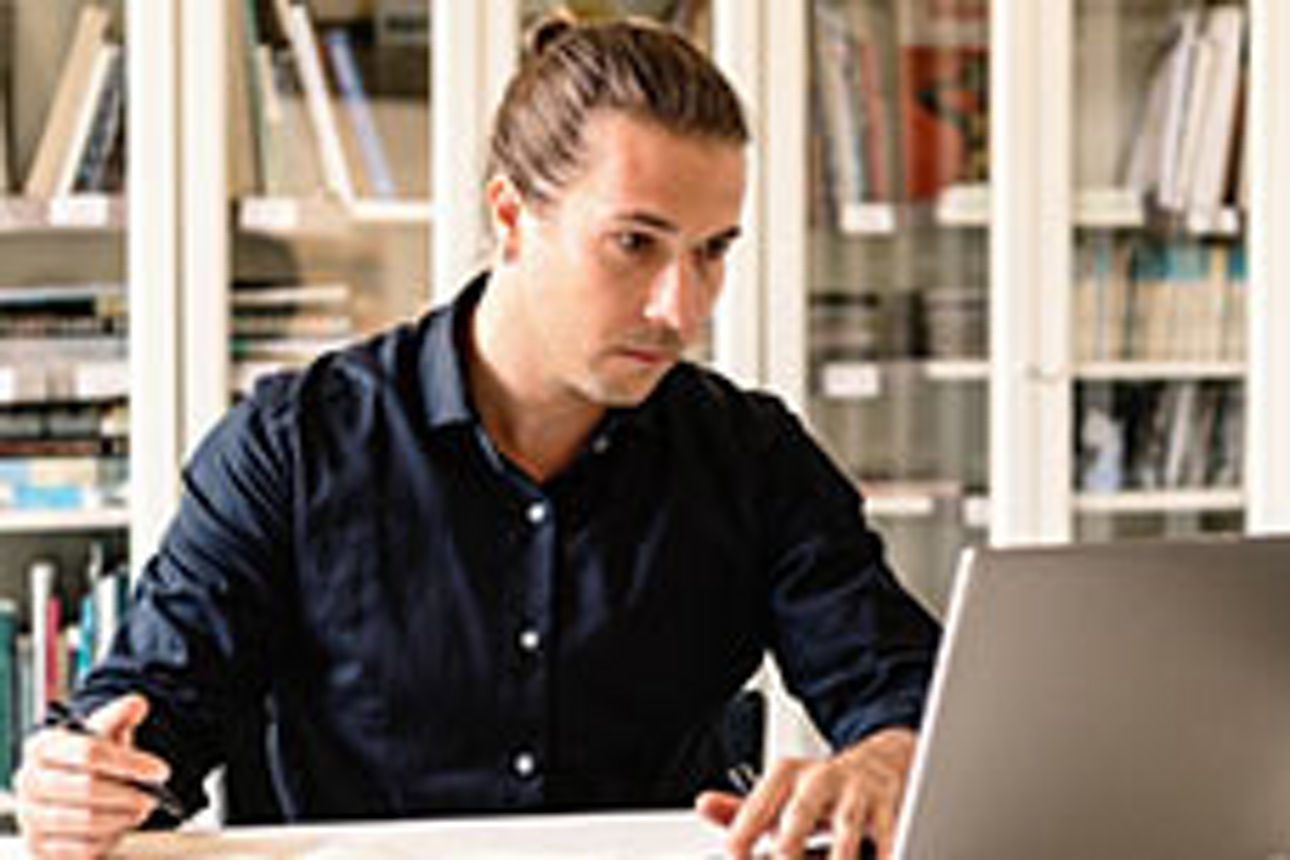 Mann sitzt in seinem Büro vor dem Laptop