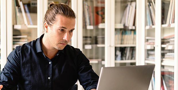 Mann sitzt in seinem Büro vor Laptop