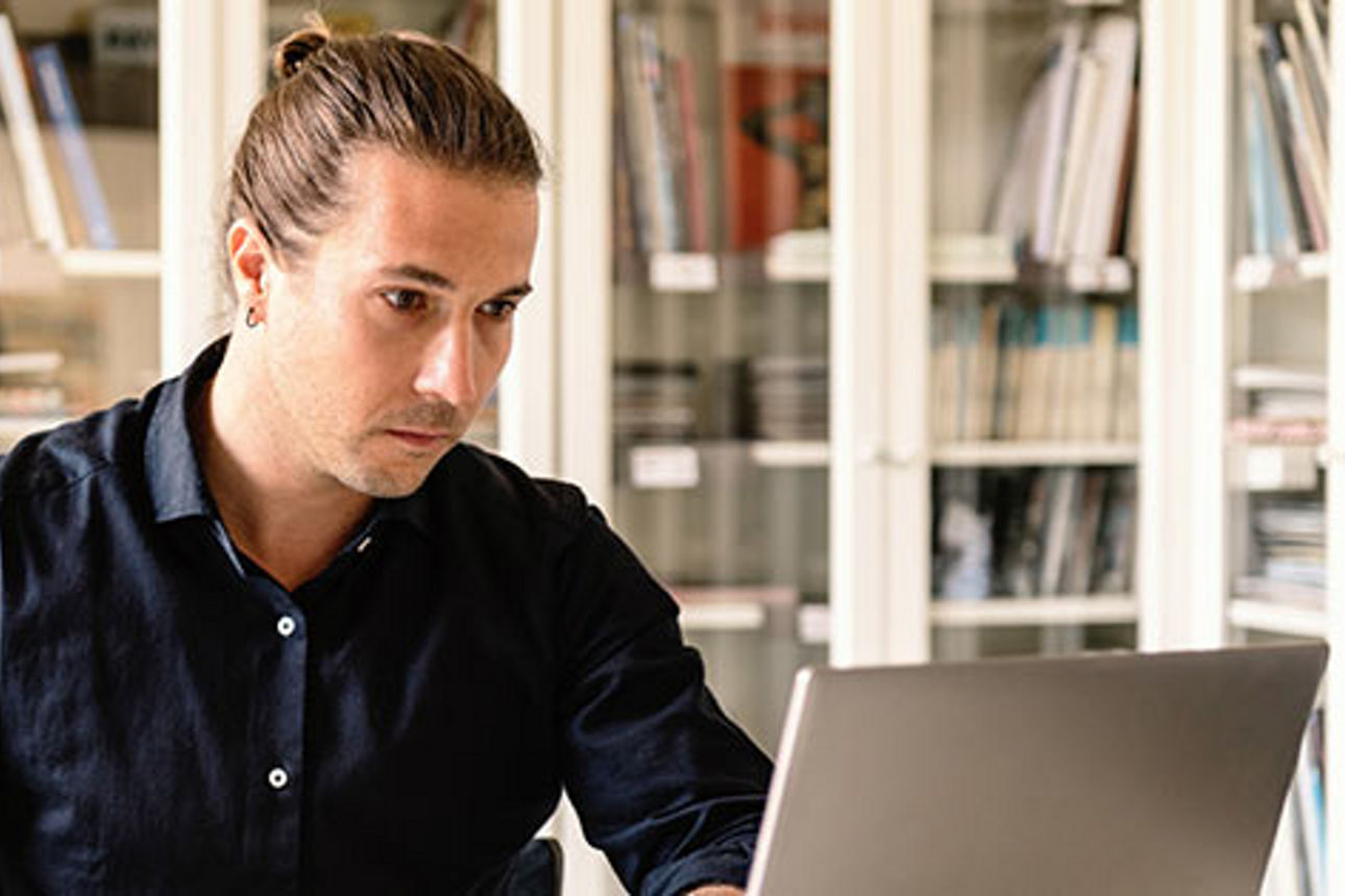 Mann sitzt in seinem Büro vor Laptop